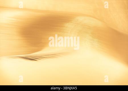 A stunning close-up of golden sand dunes, showcasing intricate textures and patterns in the warm glow of soft sunlight, capturing the essence of natur Stock Photo