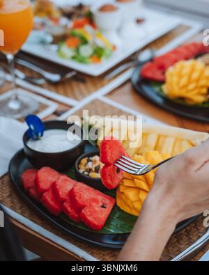 A vibrant breakfast scene at a hotel with fresh tropical fruits like watermelon and mango, served elegantly on a black platter, capturing the essence Stock Photo