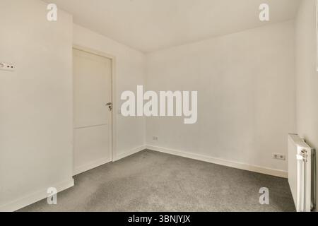 A bright, empty room featuring white walls and grey carpet, illuminated by natural sunlight. This serene space offers a neutral backdrop for any desig Stock Photo