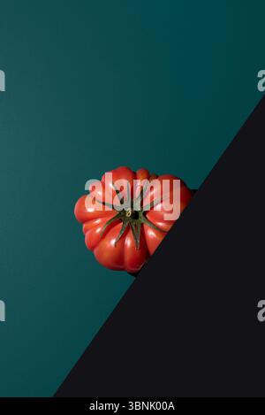 From above a fresh, ripe tomato of vibrant red hue on a contrasting dark green background, showcasing its natural beauty and texture. Perfect for prom Stock Photo