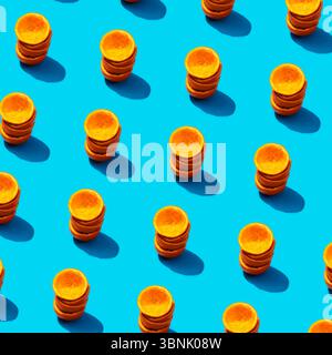 Top view of multiple stacks of freshly sliced orange discs neatly arranged on a vibrant blue background. The image captures the vivid contrast and rep Stock Photo