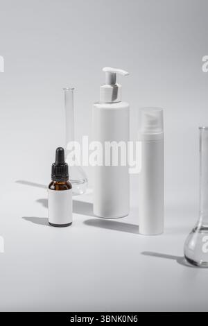 Assortment of cosmetic bottles and test tubes on a white background, capturing the essence of minimalism and luxury in skincare. Ideal for promoting b Stock Photo