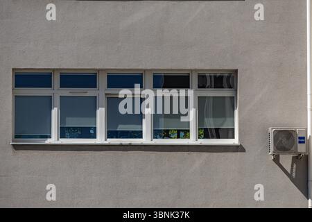Old damaged air conditioners requiring maintenance and fungicides hanging on the external wall of a public utility building, air conditioning failure, Stock Photo