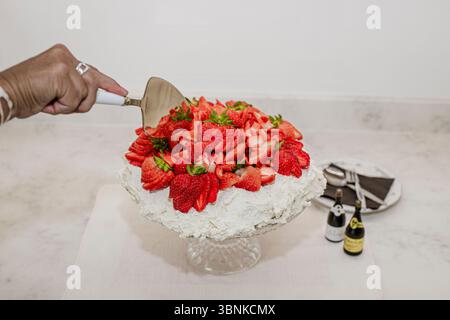 A Strawberry Pavlova is a classic dessert featuring a crispy meringue shell topped with whipped cream and fresh strawberries. Stock Photo