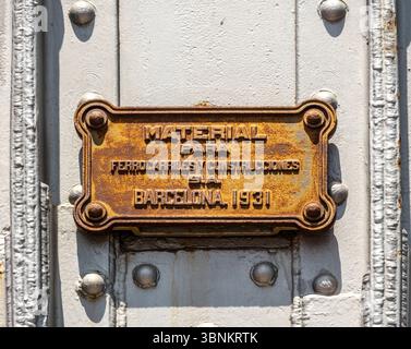 An old, rusty manufacturer's plaque from 1931 on a riveted iron structure in Barcelona. 'Material para Ferrocarriles y Construcciones S.A.' Spain. Stock Photo