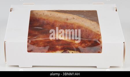 One triangular pizza slice had burnt marks in the cardboard box. Stock Photo