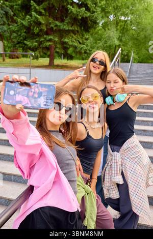 Youthful street dancers posing for selfie on urban steps with stylish outfits and vibrant energy Stock Photo