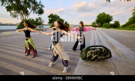 Sound in motion. Group of energetic young women practicing street dance by riverbank Stock Photo