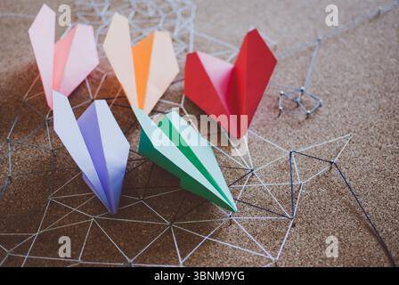 Group of colorful paper planes over the threads linking the nails. Entities connected. Abstract concept (idea) of airlines, freedom, leadership, commu Stock Photo