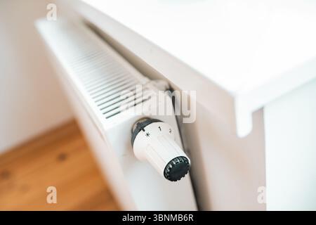 Hand regulates the heat in the house on the radiator handle. Stock Photo
