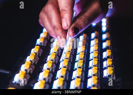 Close-up of a person cleaning yellow mechanical keyboard switches using a cotton bud. Stock Photo