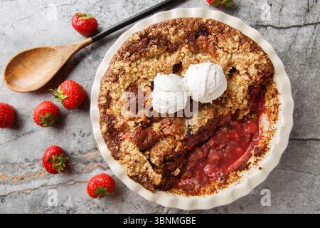 Summer dessert cocoa strawberry cobbler with vanilla ice cream close-up in baking dish on table. horizontal top view from above Stock Photo