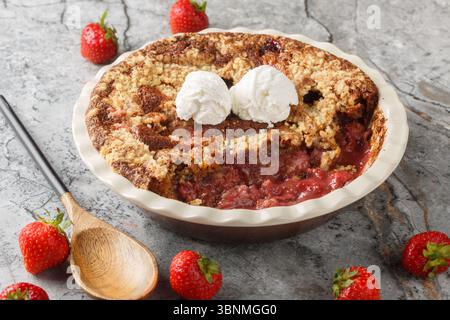 Strawberry cobbler pie with ice cream close-up in baking dish on table. Horizontal Stock Photo