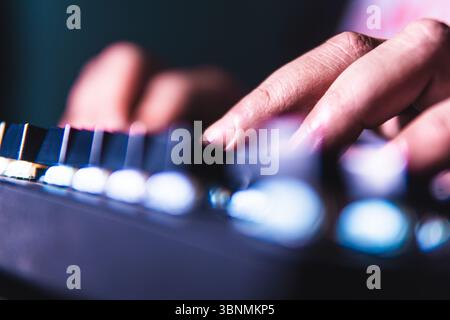 Close-up of fingers typing on a mechanical keyboard with glowing backlight. Stock Photo