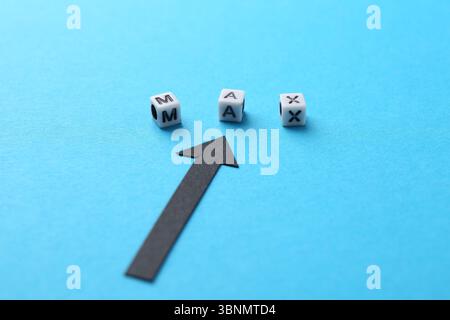 Word Max made of beads with letters and arrow pointing at it on light blue background, closeup Stock Photo
