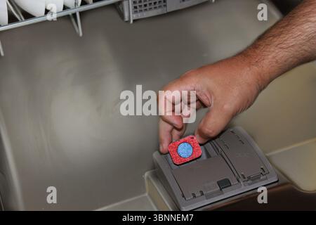 A man puts a pill in a container in a dishwasher. Stock Photo