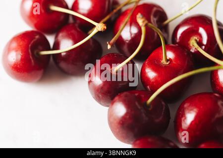 Fresh red cherries. Juicy summer fruit with stems. Close-up of ripe cherries on white background. Healthy seasonal snack. Natural sweet food. Stock Photo