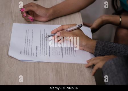 Two individuals reviewing a contract, reaching an agreement. Shot emphasizing hands and the document, suitable for business or legal topics Stock Photo