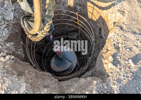 Construction equipment drilling vertical hole for a cast in place reinforced concrete pile foundation Stock Photo