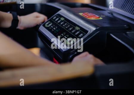 Close-up of hands adjusting the speed of a treadmill. Healthy lifestyle for a physical workout and cardio training on a modern machine at a fitness ce Stock Photo
