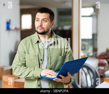 Interested young man using laptop in house during renovation Stock Photo