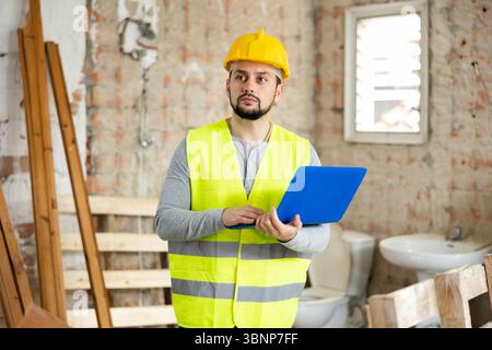 Bearded architect with laptop standing in house under reconstruction Stock Photo