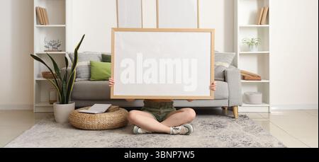 Young woman sitting on floor with big frame in living room Stock Photo