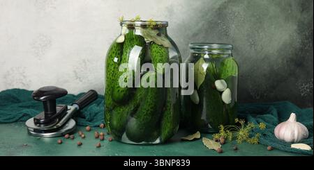 Jars with fresh cucumbers for preservation on green background Stock Photo