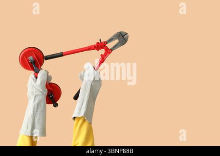 Female worker with tools on beige background Stock Photo