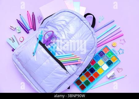 Composition with stylish school backpack and different stationery on lilac background Stock Photo