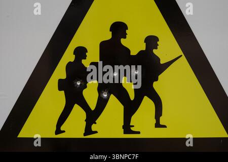 Close-up of a military area warning sign with soldier silhouettes and bullet holes. Estonia. Stock Photo