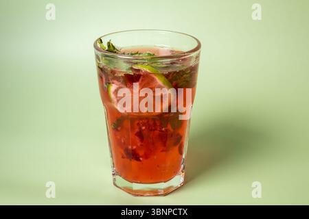 A vibrant and refreshing strawberry lime mojito in a tall glass, garnished with fresh mint leaves and a lime slice. Perfect for summer drinks, parties Stock Photo