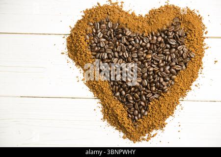 Showing flat design heart-shaped coffee beans sitting inside ground coffee border on wooden plank Stock Photo