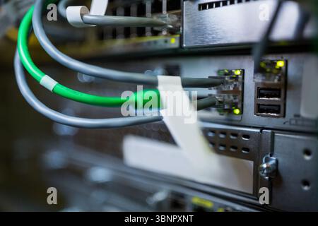 Cluster of gray and green Ethernet cables are showing glowing status lights in metal switch panel Stock Photo