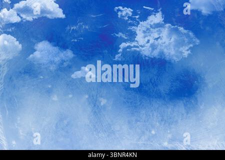Deep blue sky is spreading across canvas, showing fluffy clouds and distressed painterly texture Stock Photo