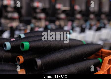 Closeup of black thread spools on yarn production line in modern textile industry manufacturing process Stock Photo