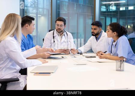A diverse medical team collaborates in a modern office setting. They are engaged in a discussion. Stock Photo