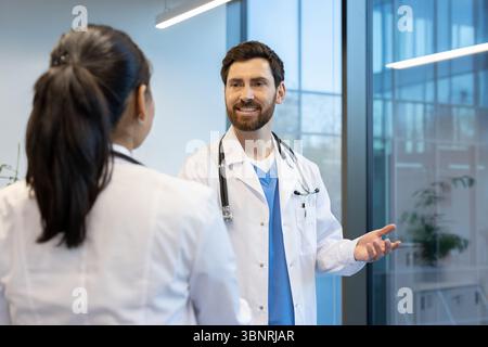 Two doctors in white coats are in conversation, the man gesturing with his hand. Stock Photo