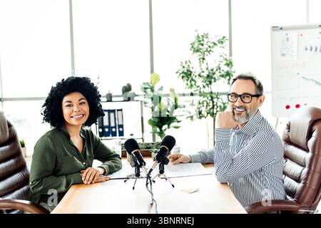 Two professionals collaborate on a podcast in a modern office workspace showcasing diversity and teamwork Stock Photo