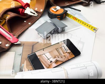 Architectural model on desk with smartphone, drawing technical tools and blueprints. Architecture, building, construction and real estate business. Stock Photo