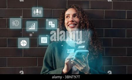 Young woman interacting with a smartphone while engaging with chatbot features against a dark brick background Stock Photo