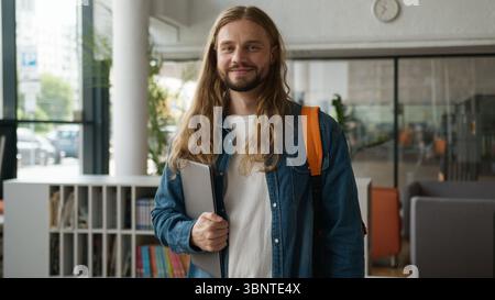 Portrait happy smiling laughing positive Caucasian man guy student male in high school library university academy looking at camera alone studying Stock Photo