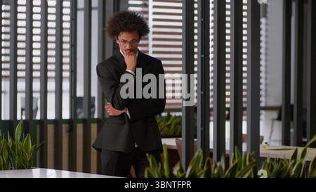 Pensive thoughtful puzzled thinking African American businessman employer developer employer business man male guy walk going walking in office ponder Stock Photo