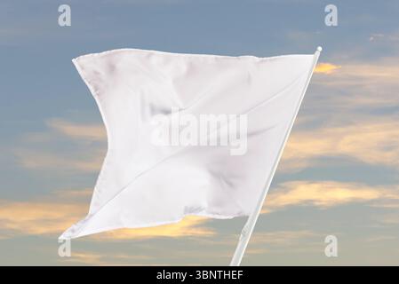 Blank white flag fluttering under sunlight, great for communication themes, clean compositions, or neutral graphic and marketing purposes Stock Photo