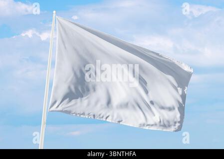 White flag waving under soft clouds, perfect for themes of surrender, calm communication, or neutral design in web or print projects Stock Photo