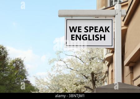 We Speak English text on advertising board in city. Language course Stock Photo