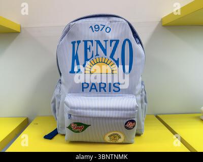 Kenzo Paris striped backpack with colorful patches displayed on a bright yellow shelf Stock Photo