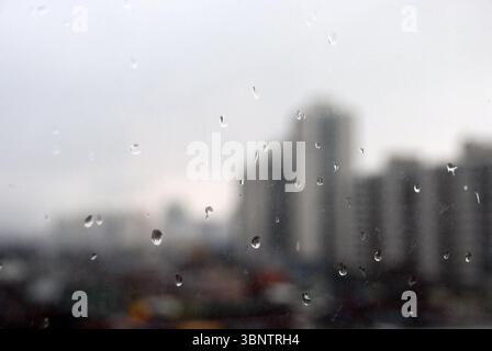 Rainy city view through window with raindrops Stock Photo