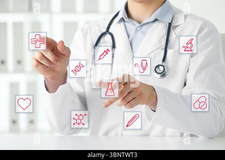 Doctor using virtual screen with healthcare icons in office, closeup Stock Photo