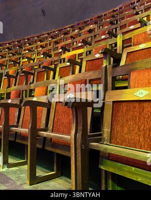 Vertical image of empty numbered wooden seats in a theater or circus auditorium. No people. Rich lighting and visual rhythm for editorial use. Stock Photo